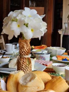 una mesa con flores blancas en un jarrón. en Confraria da Prata Flats, en Pirenópolis