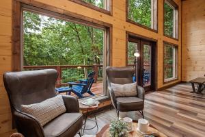 two chairs and a table in a room with windows at New Cozy Mountain Cabin Hot Tub Near Downtown in Gatlinburg