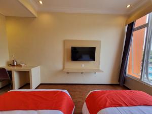um quarto com duas camas e uma televisão na parede em core inn juwita hotel em Kepanjen