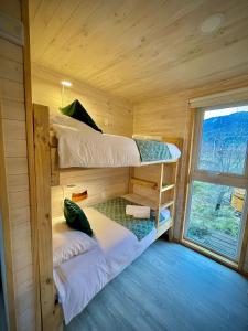 two bunk beds in a wooden cabin with a window at Refugio con calefaccion central y tinaja in Malalcahuello