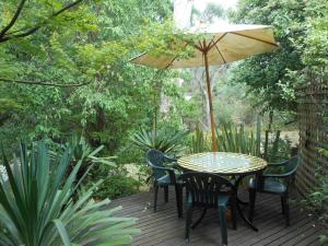 a patio table with chairs and umbrellas at Merrimeet Cottages in Bright