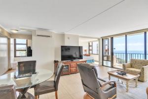 een woonkamer met een tafel en een televisie bij 37th Floor Condo with Sweeping Ocean Views & Free parking! condo in Honolulu