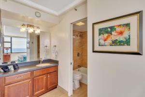 a bathroom with a sink and a toilet and a mirror at 37th Floor Condo with Sweeping Ocean Views & Free parking! condo in Honolulu