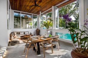 een woonkamer met een tafel, stoelen en ramen bij Villa June by BaliSuperHost in Ubud