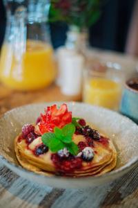 a plate of pancakes with berries and mint on a table at Mandala Ace Albany Hotel in Albany