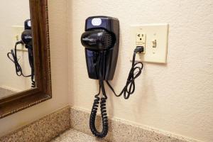 a phone hanging on a wall next to a mirror at Rosen Inn Lake Buena Vista in Orlando