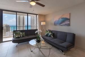 uma sala de estar com um sofá e uma mesa de vidro em Newly Remodeled Corner Unit at the Waikiki Banyan with Diamond Head Views condo em Honolulu