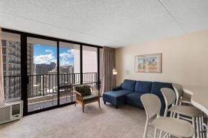 uma sala de estar com um sofá azul e uma varanda em Waikiki Banyan 28th Floor Ocean View Condo - Free parking & WiFi home em Honolulu