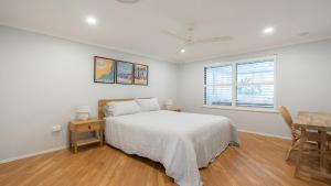 a bedroom with a bed and a table and a window at Coral Paradise - Metres From Beachfront in Pearl Beach