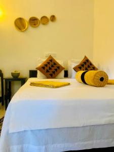 Una cama con sábanas y almohadas amarillas y blancas. en Sigiri Rock Side Home Stay en Sigiriya