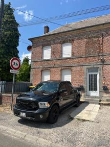 a black truck parked in front of a brick house at Piwi Thierache 