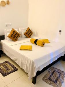 a white bed with yellow and black pillows on it at Sigiri Rock Side Home Stay in Sigiriya