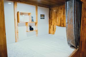 a bed in a small room with wooden walls at The Dorm Tam Toà in Xóm Ðé