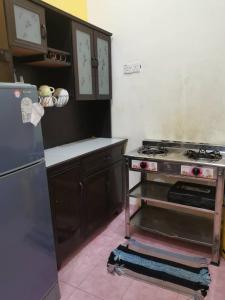 a kitchen with a stove and a refrigerator at Teratak Tuan Muda Homestay in Melaka