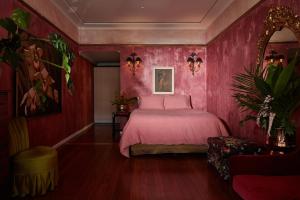 a pink bedroom with a bed and a chair at Eltham Hotel NSW in Eltham