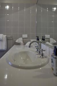 lavabo blanco en el baño con espejo en Eltham Hotel NSW, en Eltham