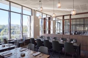 un restaurante con mesas, sillas y ventanas grandes en RACV Healesville Country Club & Resort, en Healesville