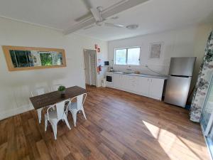 een keuken met een tafel en stoelen en een koelkast bij Castaways Moreton Island in Bulwer