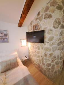 a living room with a stone wall with a tv at Danino in Jezera