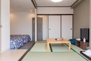 a room with a table and a bed and a tv at 紀州鉄道片瀬江ノ島ホテル in Fujisawa