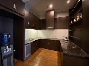 a kitchen with black cabinets and a wooden floor at Golden Flower by KAGUM Hotels in Bandung