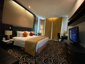 バンドンにあるGolden Flower by KAGUM Hotelsのベッド1台、薄型テレビが備わるホテルルームです。