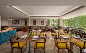 un restaurante con mesas de madera y sillas amarillas en The Neemaya en Kāndla