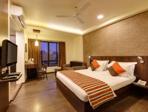a hotel room with a bed and a television at Regenta Place Raysons Kolhapur in Kolhapur