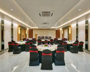 un salón de banquetes con mesas y sillas en una habitación en Regenta Place Raysons Kolhapur, en Kolhapur