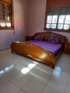 Cama grande de madera en habitación con ventana en Apartment El Jadida en El Jadida