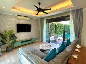 a living room with a couch and a flat screen tv at The Kiri Villas Resort in Thalang