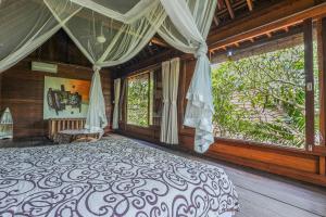 a bedroom with a large bed and large windows at Sari Bamboo Bungalows in Ubud