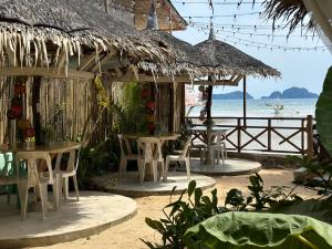 a restaurant with tables and chairs on the beach at Panari Lodge El Nido in El Nido