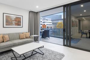 Meriton Suites Canberra في كانبرا: غرفة معيشة مع أريكة وطاولة