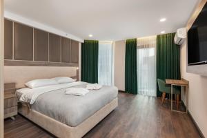 a bedroom with a bed with green curtains and a television at Wyn Residence Batumi in Batumi +21 photos