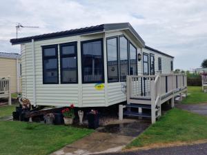 a small white tiny house with a porch at Jasmine's Retreat - Pet friendly, Ingoldmells in Ingoldmells