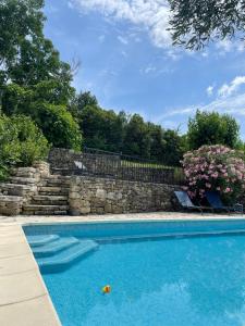 una piscina con una pared de piedra y flores en Gîte passiflore, en Frigoulet