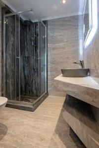 a bathroom with a glass shower and a sink at Velky Sen Luxury Apartments in Sarti