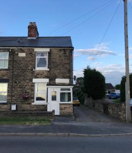 a brick house with a white door on a street at Hilltop Cottage in Renishaw