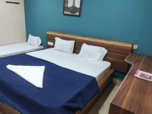 2 camas en una habitación con una pared azul en Hotel Cauvery, en Visakhapatnam