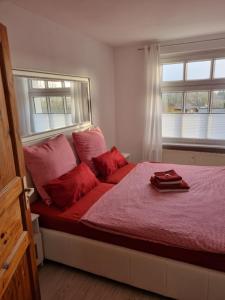 Katzow的住宿－Storchenhof Engel，一间卧室配有一张红色床单和两个窗户。