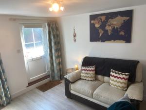 a living room with a couch and a window at Woodbridge - Cosy little 2-Bed Cottage in Woodbridge