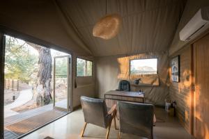 Zimmer mit einem Schreibtisch und Stühlen in einem Zelt in der Unterkunft Nkuhlu Tented Camp in Skukuza