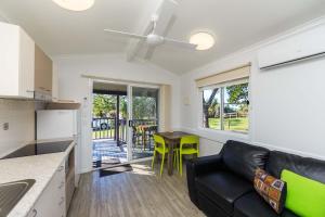 een woonkamer met een zwarte bank en een keuken bij Reflections Corindi Beach - Holiday Park in Corindi
