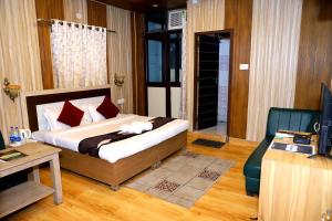 um quarto com uma cama, uma secretária e uma televisão em Hotel The Mountain View em Rishikesh