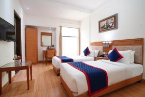 um quarto de hotel com duas camas e uma mesa em Zip By Spree Hotels Delhi Greater Kailash em Nova Deli