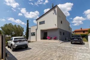 ein weißes Haus mit zwei Autos, die in einer Einfahrt geparkt sind in der Unterkunft Beautiful villa Eva with private pool near the beach in Šišan