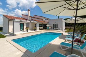 eine Villa mit Swimmingpool und Sonnenschirm in der Unterkunft Beautiful villa Eva with private pool near the beach in Šišan