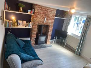 a living room with a couch and a brick fireplace at Woodbridge - Cosy little 2-Bed Cottage in Woodbridge