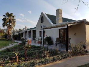 a white house with a porch and a palm tree at Silos Guesthouse in Addo
